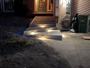 Concrete entryway with recessed LED lighting along walkway and landing