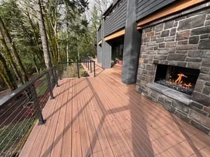 Composite deck with metal railings and stone fireplace with active fire insert