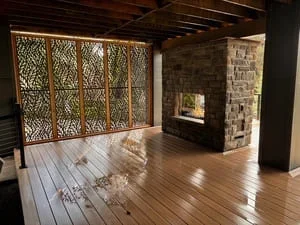 Hardwood flooring, metal divider panels, and stone fireplace in renovated interior space