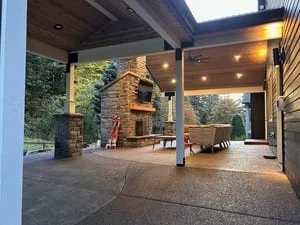 Covered patio with steel beams, brick fireplace, stamped concrete floor, and ambient lighting