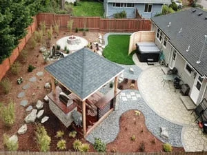 Aerial view of new composite deck with shade structure, concrete patio, and landscaping in residential backyard