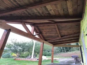 Timber frame pavilion with exposed beams, cross-bracing, and wood ceiling under construction